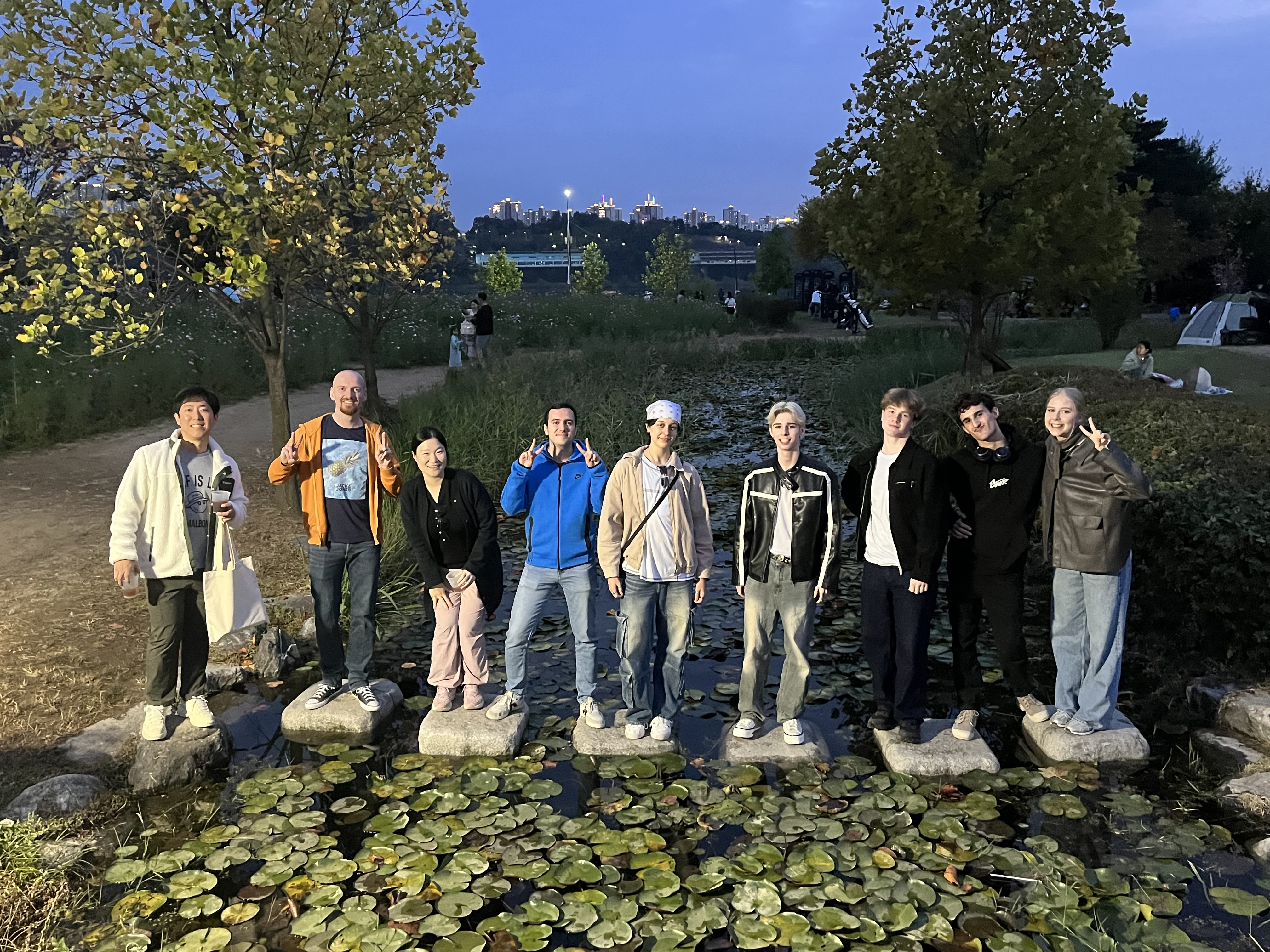 Large group of guests posing together at a park in the evening